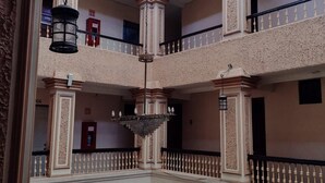 A multi-level atrium with a central open space, columns, and hanging lanterns. - Hotel Metropolitan (Guadalajara)