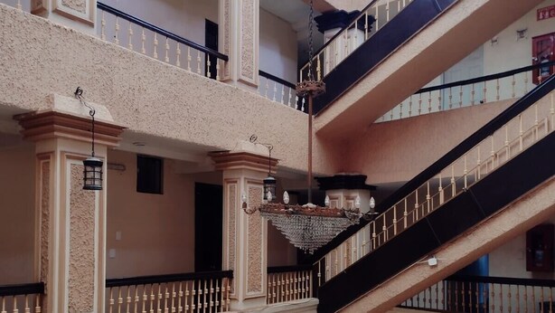 A multi-level atrium with a central staircase, decorative railings, and potted plants. - Hotel Metropolitan (Guadalajara)