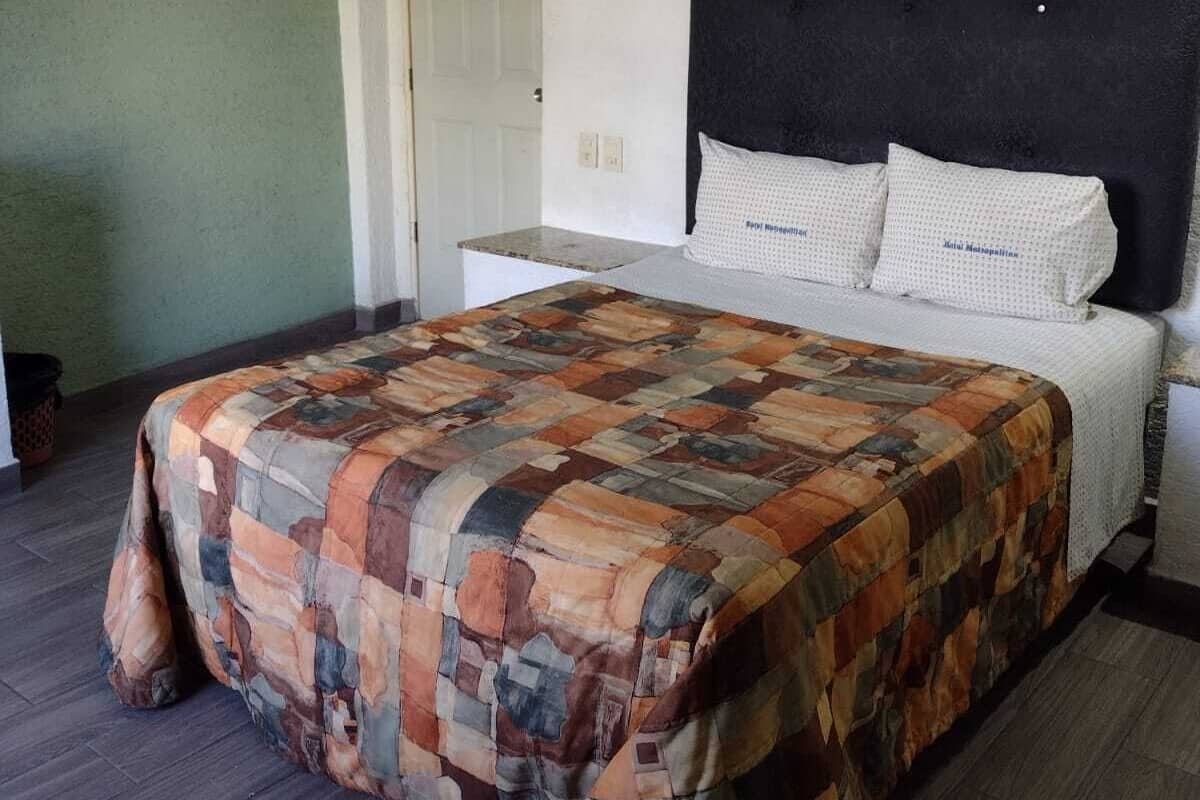 Un dormitorio con una cama, un cabecero, una puerta y una pared con un calendario.