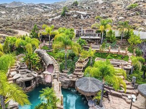 A resort with a pool, tropical plants, and a rocky landscape. - Hidden Oasis - Paradise Getaway - Sleeps 25 Guest (Moreno Valley)