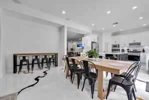 Una cocina moderna con armarios blancos, una mesa de comedor de madera y sillas negras.