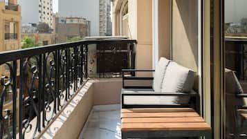 A balcony with a wooden bench, a hanging light fixture, and a view of surrounding buildings.