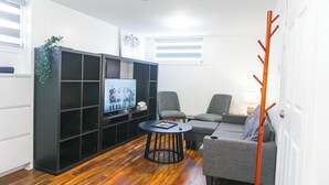 Un salon moderne avec un meuble de rangement noir pour les appareils électroniques, des canapés gris et un plancher en bois.