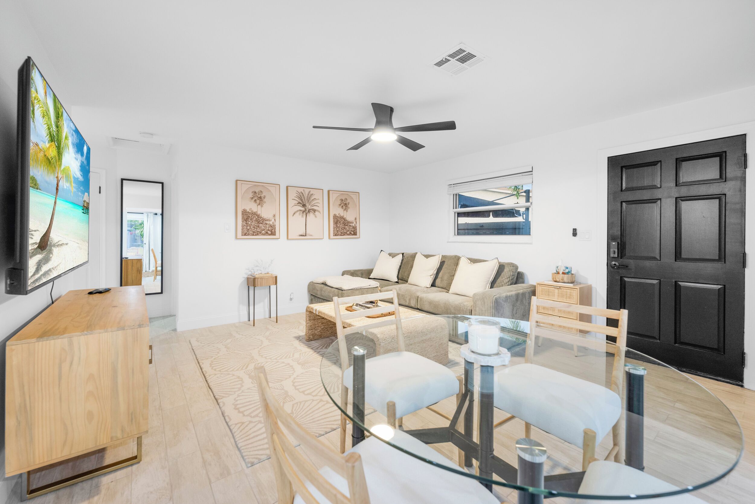 Una sala de estar moderna con una mesa de comedor de vidrio, un sofá y un ventilador de techo.