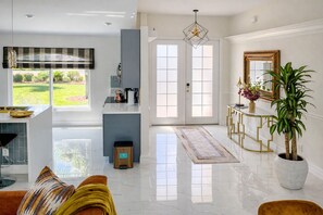Una cocina moderna con una isla central, un rincón de comedor con un sofá y un amplio ventanal con vistas a un jardín.