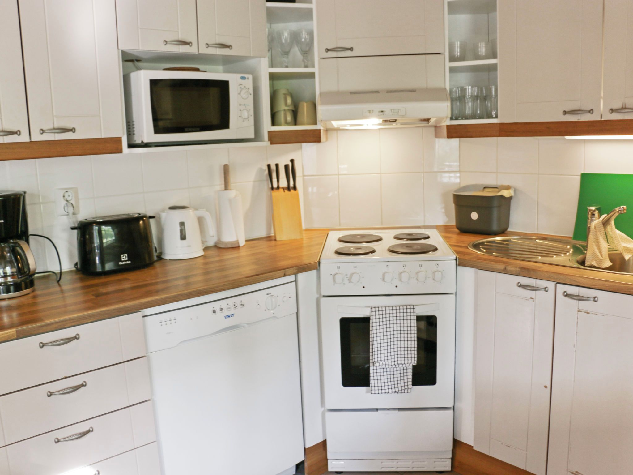 Une cuisine avec des appareils électroménagers blancs, des plans de travail en bois et des armoires blanches.