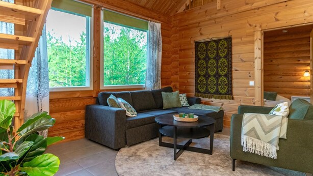 A cozy log cabin interior with a sofa, a round coffee table, and a green armchair.