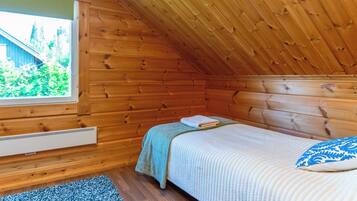 A cozy cabin room with a bed, a window, and an exit sign.