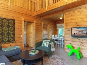 A log cabin interior with a dining area, a television mounted on the wall, and a green plastic chair. - Vacation home Susi by Interhome (Savonlinna)