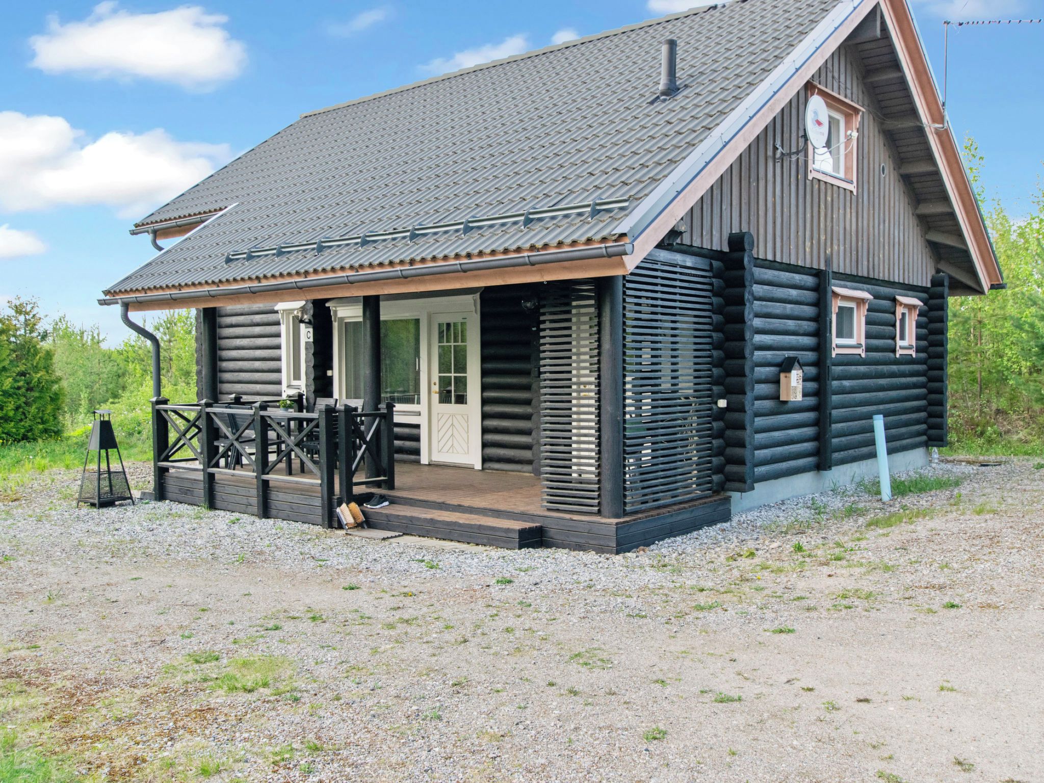 A log cabin with a porch, a chimney, and a satellite dish.