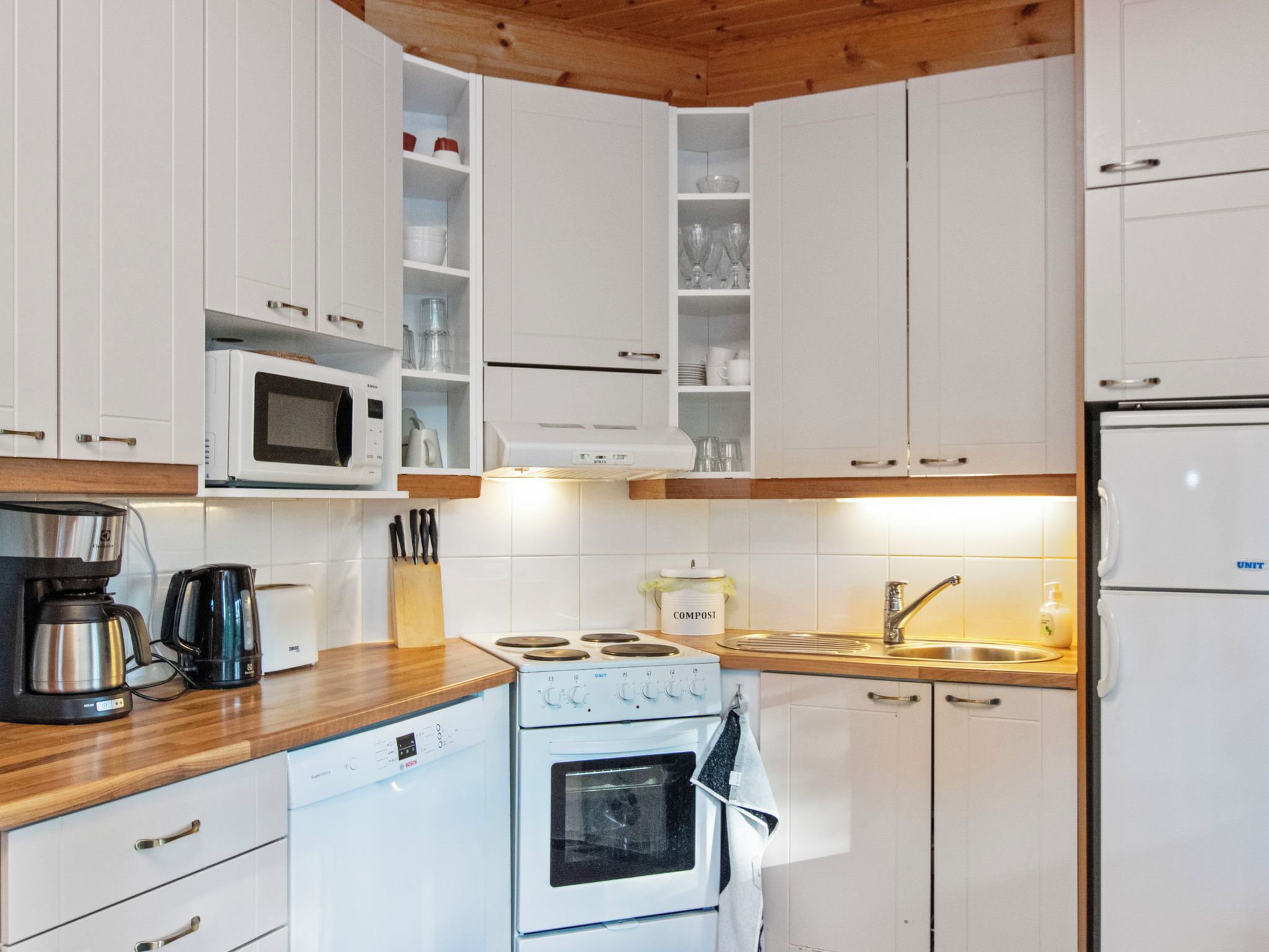 A modern kitchen with white cabinetry, a built-in microwave, a stove, and a sink.