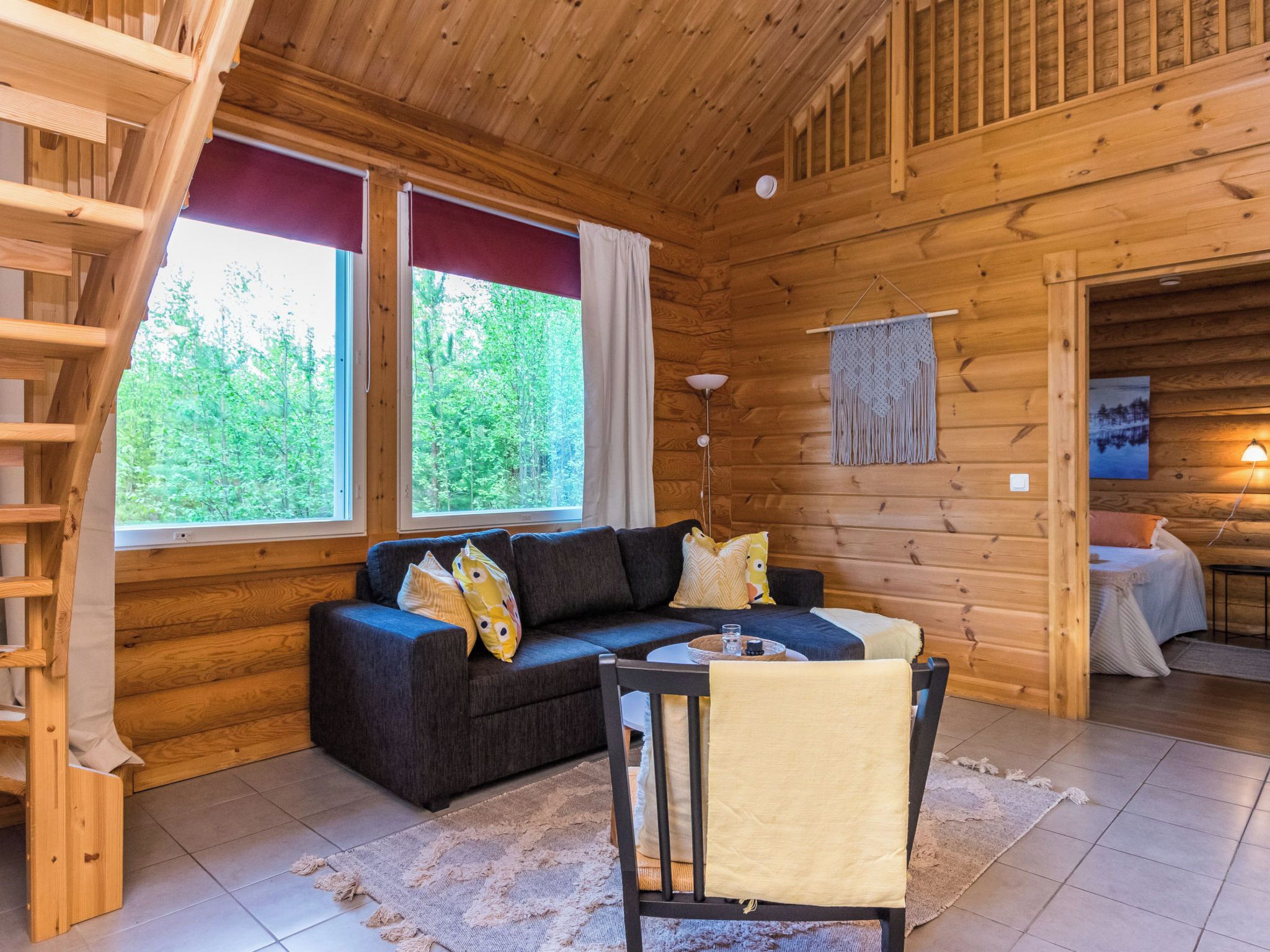 Ein gemütliches Blockhaushaus-Interieur mit einer Couch, einem Sessel, einem Tisch und einer Treppe.