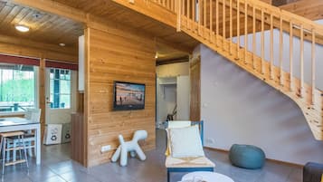 A spacious living area with a wooden staircase, a dining table, and a cozy seating arrangement.