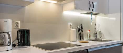 Una cocina moderna con estufa integrada, cafetera y lavaplatos.