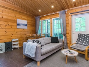 Une pièce chaleureuse avec un canapé gris, un fauteuil orné d’un coussin à motifs étoilés, une petite table avec un plateau et un tableau accroché au mur.