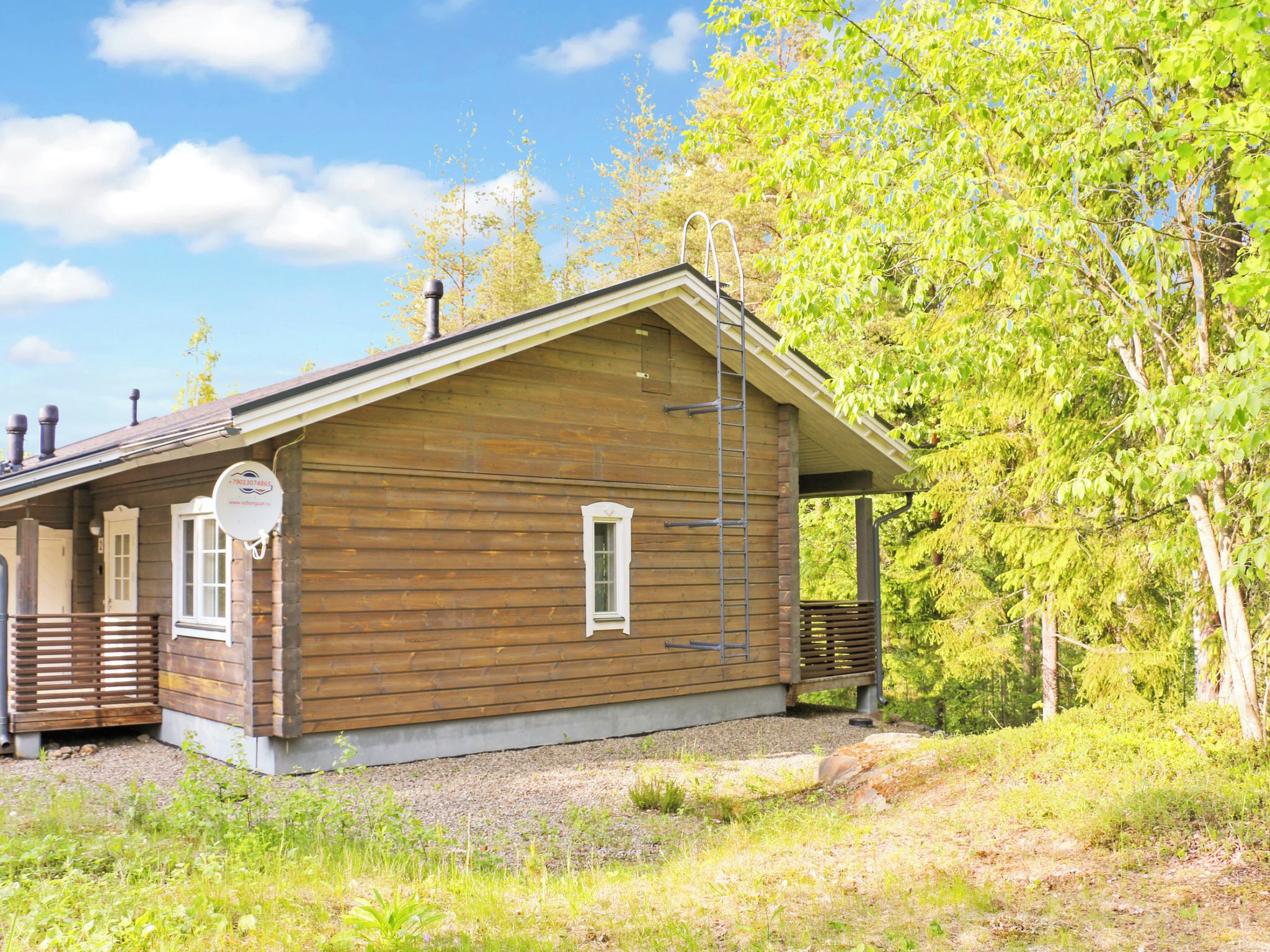 A wooden cabin with a porch, a ladder, and a small window.