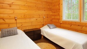 Een houten kamer met twee bedden, een raam en een kleine tafel.