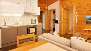 Een moderne keuken met witte kasten, een houten plafond en een eethoek met een houten tafel en stoelen.