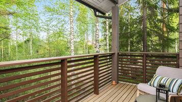 A wooden deck with a railing, a cushioned bench, and a small table with a lantern.