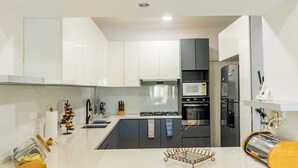 Uma cozinha moderna com armários brancos, uma ilha central, eletrodomésticos de aço inoxidável e uma torradeira.