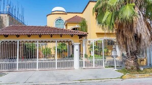 Um edifício amarelo com uma cúpula, área cercada e uma palmeira.