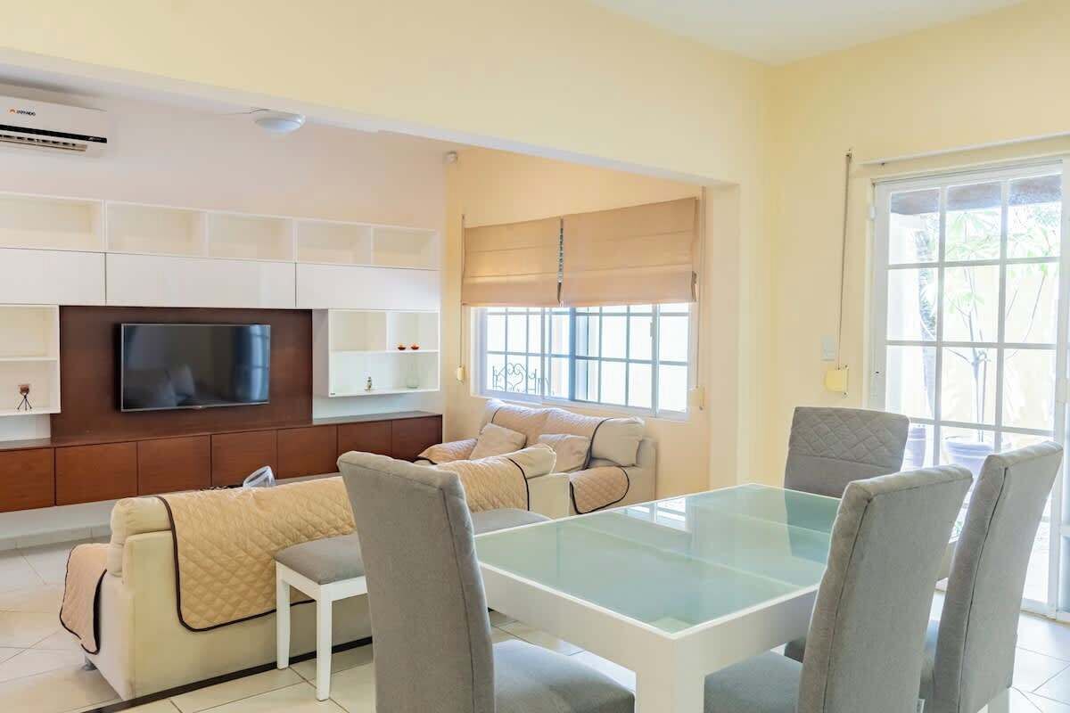 A living room with a TV, sofa, and dining table.