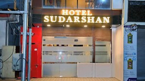 Exterior del Hotel Sudarshan, con un letrero destacado, una puerta roja y una entrada con azulejos.