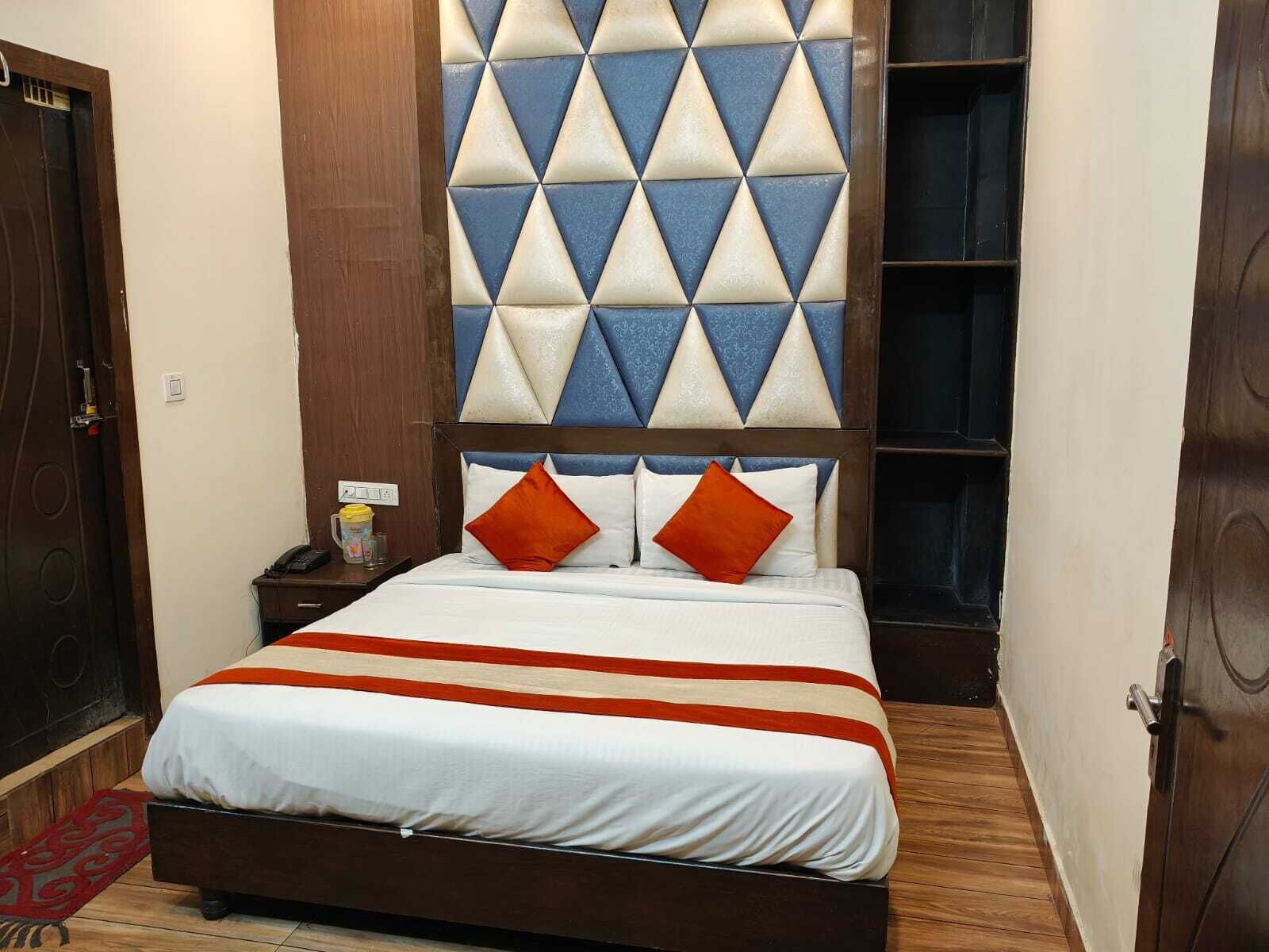A neatly made bed with a striped bedspread, two pillows, and a headboard with a geometric pattern.