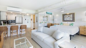 Une chambre d’hôtel moderne équipée d’une kitchenette, d’un canapé, d’un lit et d’un coin repas avec des tabourets de bar.