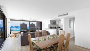 Un espace de vie moderne comprenant une table à manger, des chaises, un canapé et une vue sur la plage.
