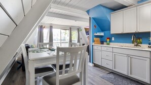 A kitchen with white cabinets, a blue accent wall, and a dining area with a table and chairs.