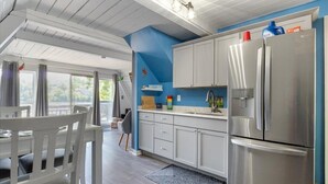A modern kitchen with white cabinets, a stainless steel refrigerator, and a blue accent wall.