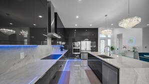 A modern kitchen with a central island, stainless steel appliances, and pendant lighting.
