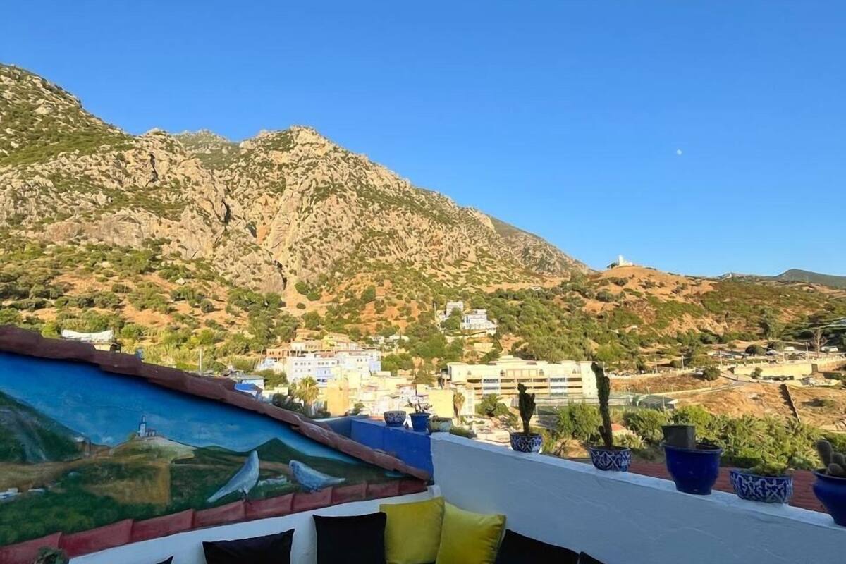 A terrace with a view of a mountain, a pool, and a table with chairs.