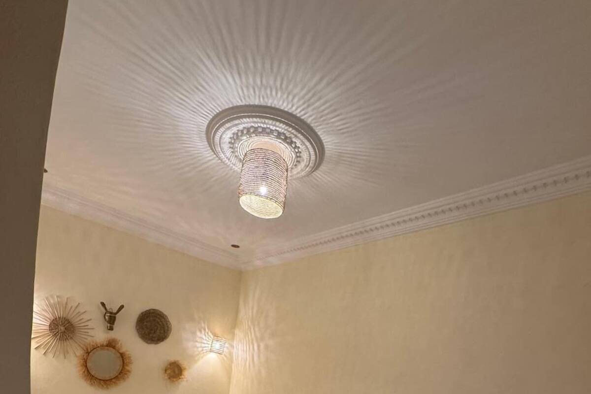 A bedroom with a bed, a sofa, decorative wall art, and a ceiling light fixture.