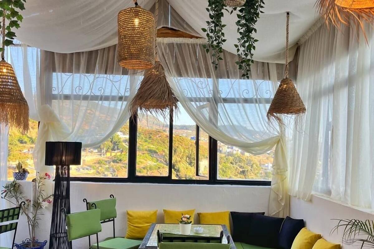 A cozy interior with a green sofa set, a tiled table, and hanging wicker lamps.