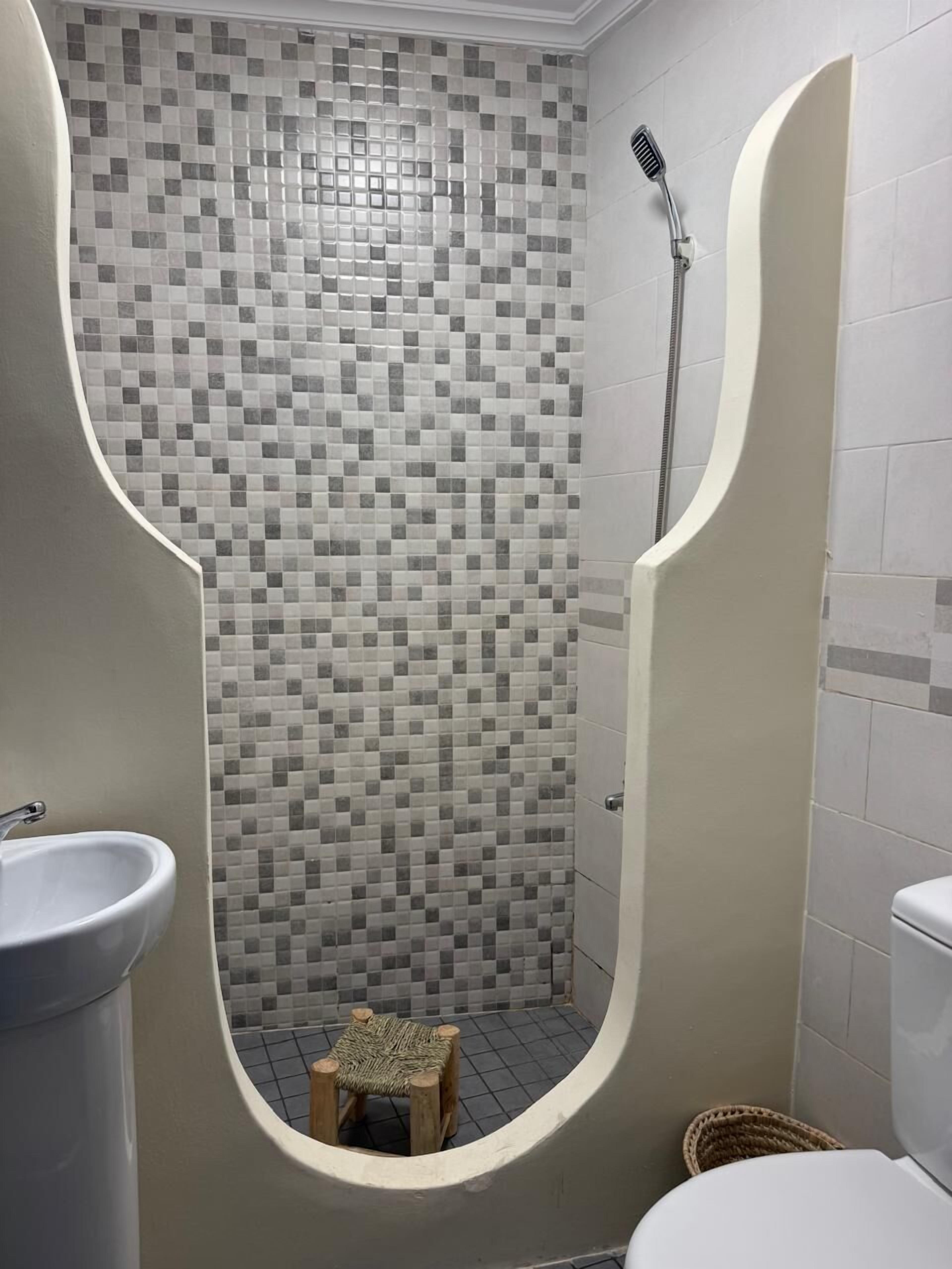 Un baño con ducha azulejada, lavabo e inodoro.