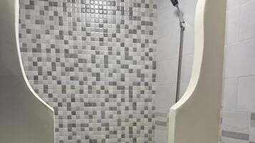Un baño con ducha azulejada, lavabo e inodoro.