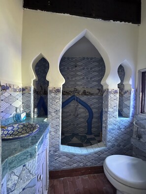 A bathroom with a stone mosaic wall, a sink with a decorative basin, and a toilet. - Mount Chaouen (Chefchaouen)