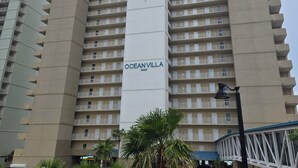 Un hôtel de grande hauteur appelé Ocean Villa, doté d’une tour centrale, de nombreux balcons et d’un espace paysager environnant agrémenté de palmiers.