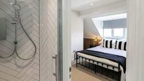 Un dormitorio moderno con una cama grande, cabina de ducha de vidrio y tragaluz.