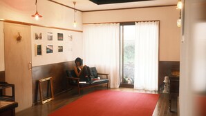 Ein Zimmer mit rotem Teppich, einer schwarzen Couch, einem Klavier und einer Wand mit gerahmten Bildern.