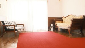A room with a red carpet, a sofa, a chair, and a lamp. - Guest House SAKURAZUKISOU - Hostel (Kagoshima)