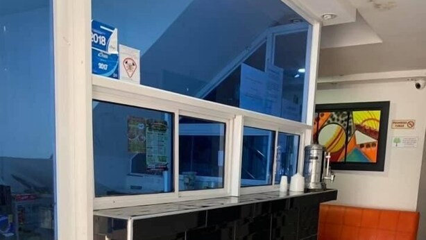A reception area with a black tiled wall, a blue window, and a small white stool. - Torres del Parque 1 (Soledad)