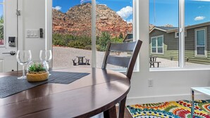 A dining area with a table, chairs, and a view of a mountain through large windows. - Chimney Rock Suite - Unit C - Red Rock Retreat (Sedona)