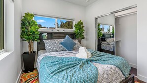 A bedroom with a bed, two potted plants, a window, and a mirror. - Chimney Rock Suite - Unit C - Red Rock Retreat (Sedona)