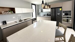 A modern kitchen with a central island, stainless steel appliances, and pendant lighting.