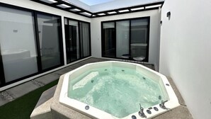 A modern outdoor hot tub area with a clear view of the sky, surrounded by large sliding glass doors and a minimalist architectural design.
