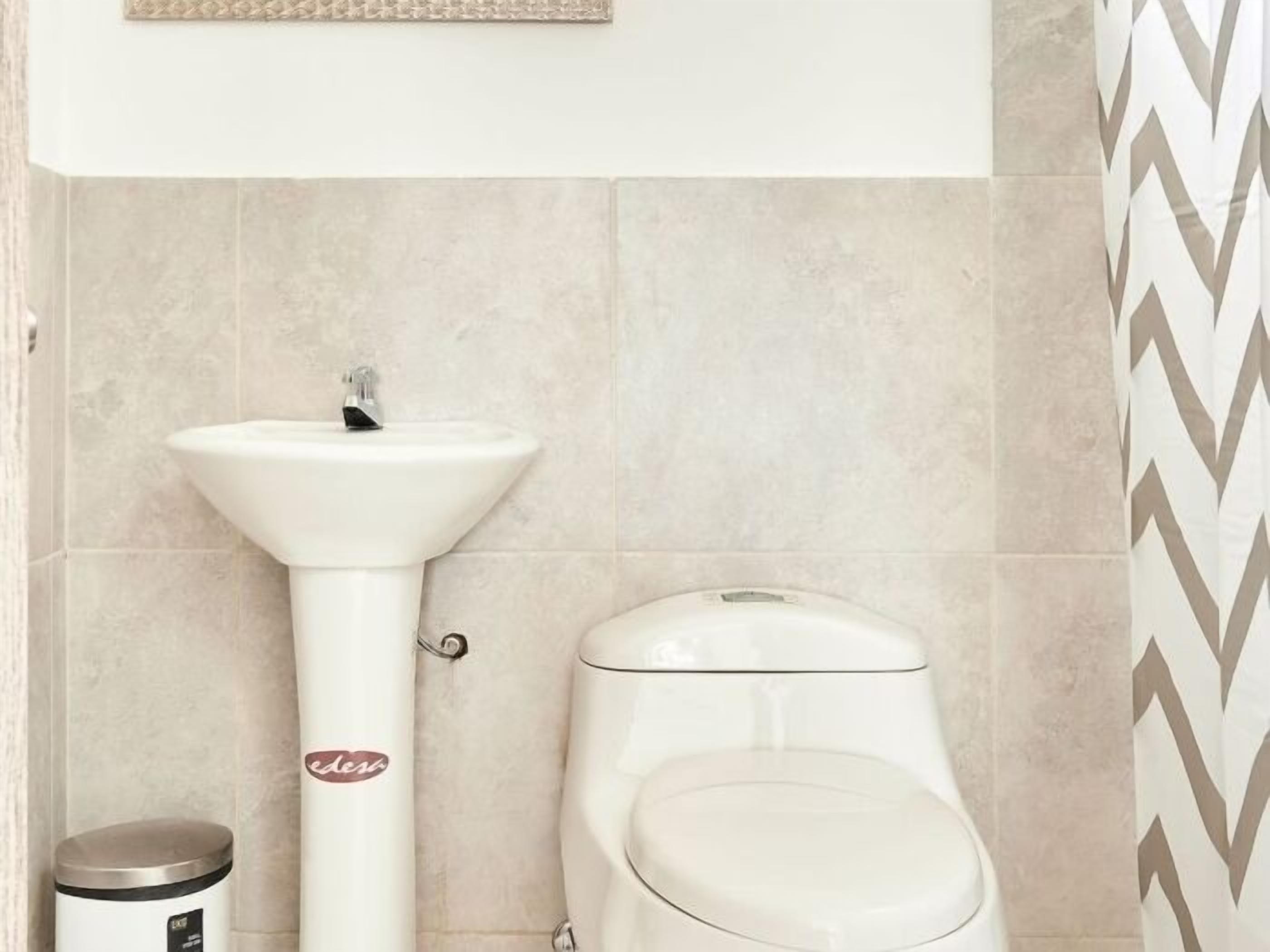Ein Badezimmer mit einem weißen Waschtisch, einer Toilette und einem Mülleimer.