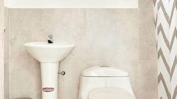Ein Badezimmer mit einem weißen Waschtisch, einer Toilette und einem Mülleimer.
